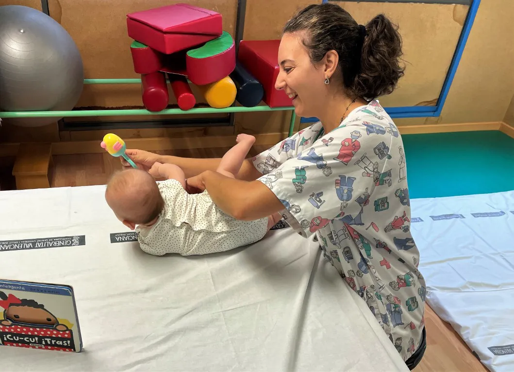 fisioterapeuta infantil trabaja los ejercicios de estimulación con una bebé en el hospital de Sant Joan